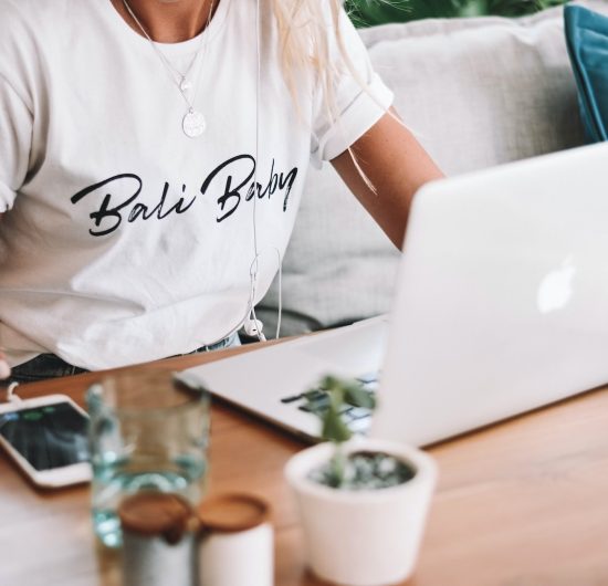 woman in white crew neck t-shirt sitting by the table with macbook