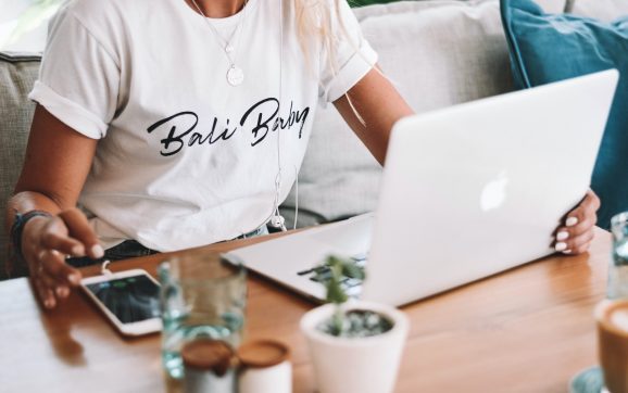 woman in white crew neck t-shirt sitting by the table with macbook