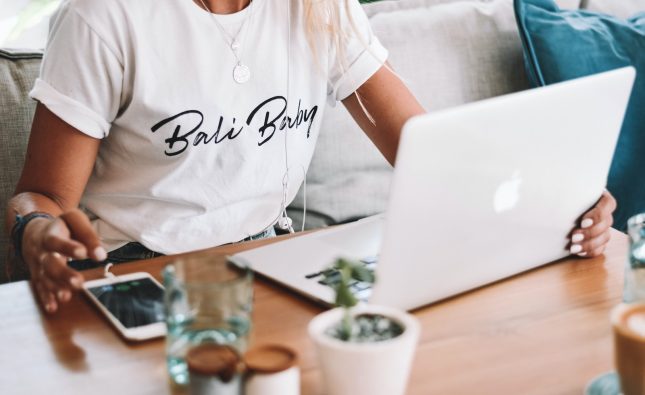 woman in white crew neck t-shirt sitting by the table with macbook