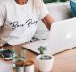woman in white crew neck t-shirt sitting by the table with macbook