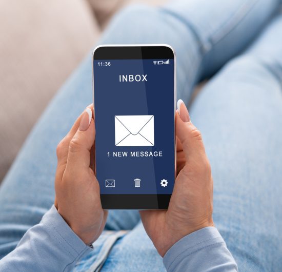 Woman Reading E-Mail Message On Smartphone Sitting On Couch Indoor